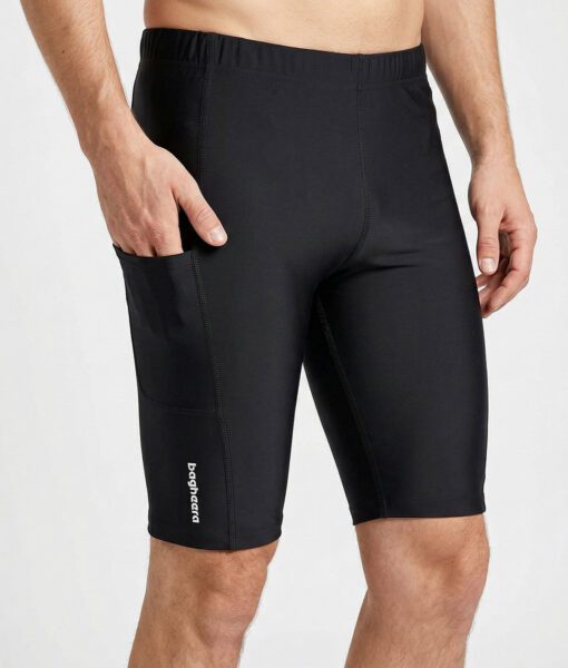 Manlig modell visar ett par svarta korta tights. Modellen har ena handen i fickan för att visa att tightsen har fickor. Modellen står framifrån i en studio med ljusgrå bakgrund.