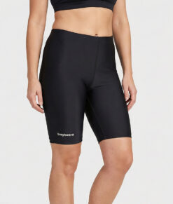 Kvinnlig modell visar ett par svarta korta tränings tights. Modellen står framifrån i en studio med ljusgrå bakgrund.