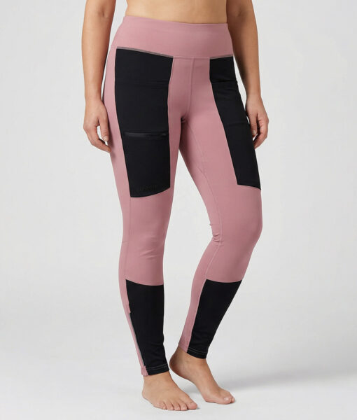 Kvinnlig modell visar ett par rosfärgade och svarta slitstark trail tights. Modellen står framifrån i en studio med ljusgrå bakgrund.