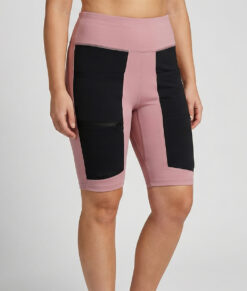 Kvinnlig modell visar ett par rosfärgade och svarta slitstark korta trail tights. Modellen står framifrån i en studio med ljusgrå bakgrund.
