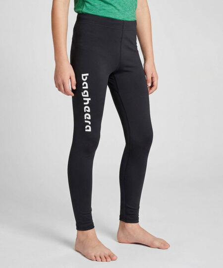 En killmodell i 12 års åldern visar ett par svarta enklare långa tights. Modellen står framifrån i en studio med ljusgrå bakgrund.