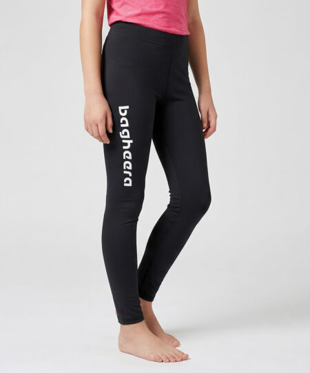 En tjejmodell i 12 års åldern visar ett par svarta enklare långa tights. Modellen står framifrån i en studio med ljusgrå bakgrund.