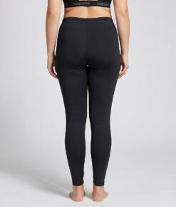 Kvinnlig modell visar ett par svarta mjuka och följsamma tights. Modellen står bakifrån i en studio med ljusgrå bakgrund.