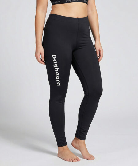 Kvinnlig modell visar ett par svarta mjuka och följsamma tights. Modellen står framifrån i en studio med ljusgrå bakgrund.