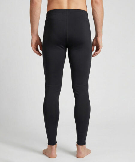 Manlig modell visar ett par svarta långa tights. Modellen står bakifrån i en studio med ljusgrå bakgrund.