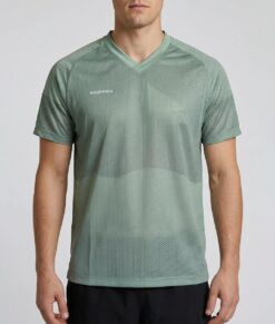 Manlig modell visar en ljusgrön luftig orienterings t-shirt i unisexmodell. Modellen står framifrån i en studio med ljusgrå bakgrund.