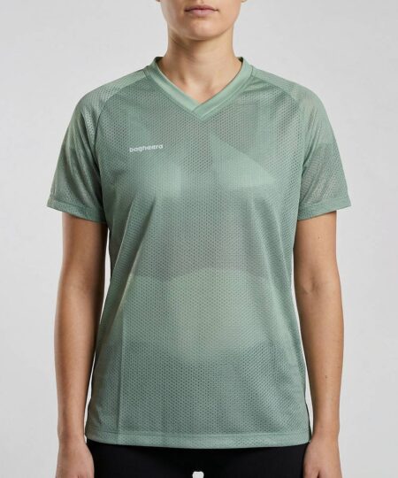 Kvinlig modell visar en ljusgrön luftig orienterings t-shirt i unisexmodell. Modellen står framifrån i en studio med ljusgrå bakgrund.