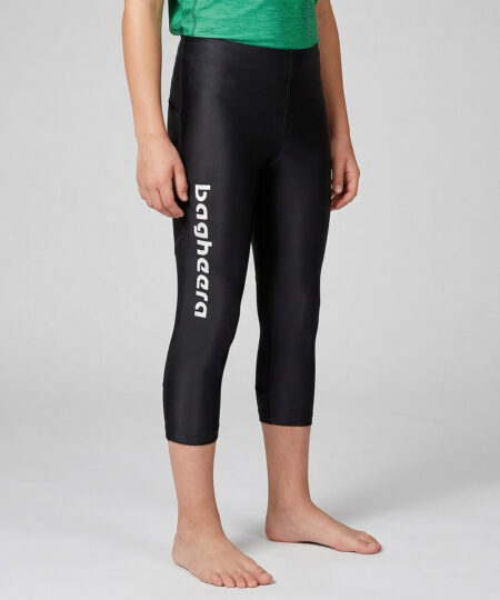 En killmodell på 12 år visar ett par svarta 3/4 långa race tights. Modellen står framifrån i en studio med ljusgrå bakgrund.