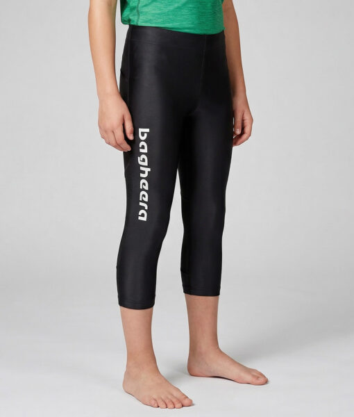 En killmodell på 12 år visar ett par svarta 3/4 långa race tights. Modellen står framifrån i en studio med ljusgrå bakgrund.