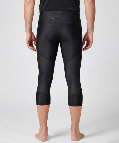 Manlig modell visar ett par svarta trekvarts långa race tights. Modellen står bakifrån i en studio med ljusgrå bakgrund.