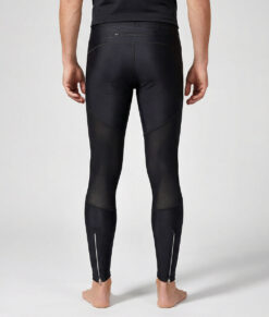 Manlig modell visar ett par svarta långa tights. Modellen står framifrån i en studio med ljusgrå bakgrund.