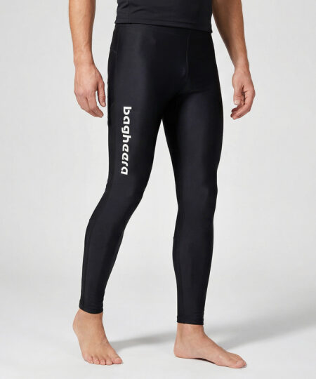 Manlig modell visar ett par svarta långa tights. Modellen står framifrån i en studio med ljusgrå bakgrund.