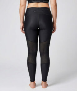 Kvinnlig modell visar ett par svarta race tights. Modellen står bakifrån i en studio med ljusgrå bakgrund.