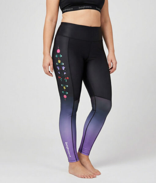 Kvinnlig modell visar ett par svarta lavenderfärgade löpartights med hög midja och mönster från dalarna. Modellen står framifrån i en studio med ljusgrå bakgrund.
