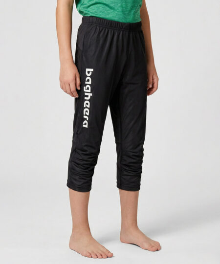 Killmodell i 12 års åldern visar ett par svarta knälånga tunna orienteringsbyxor. Modellen strår snett framifrån i en studio med ljusgrå bakgrund.