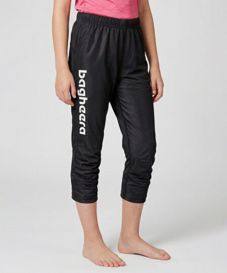 Tjejmodell i 12 års åldern visar ett par svarta knälånga tunna orienteringsbyxor. Modellen strår snett framifrån i en studio med ljusgrå bakgrund.