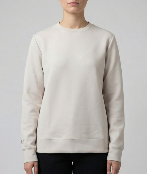 Kvinlig modell visar vår sandfärgade unisex Cloud Crew Neck tröja framifrån mot en ljusgrå bakgrund.