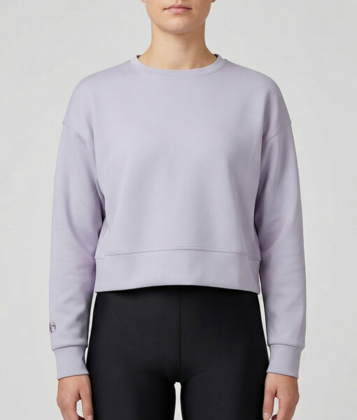 Kvinlig modell visar vår lavendelfärgade magkorta Cloud Crop Sweater framifrån mot en ljusgrå bakgrund.
