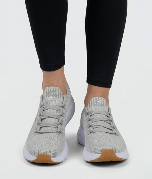 Female model shows off a sand colored Bagheera Phoenix sneaker. The model is standing from the front in a studio with a light gray background.