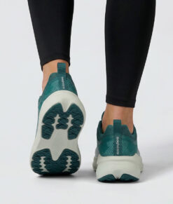 Kvinlig modell visar en grå djuphavsblå bagheera sigma sneaker. Modellen står bakifrån i en studio med ljusgrå bakgrund.