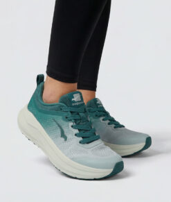 Kvinlig modell visar en grå djuphavsblå bagheera sigma sneaker. Modellen står framifrån i en studio med ljusgrå bakgrund.