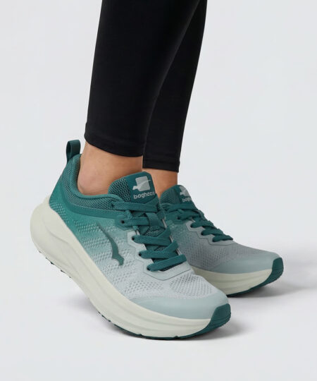Female model shows off a grey deep sea blue bagheera sigma sneaker. The model is standing from the front in a studio with a light grey background. 