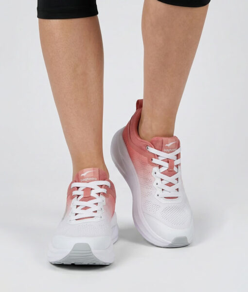 Kvinlig modell visar en vit rosa bagheera sigma sneaker. Modellen står framifrån i en studio med ljusgrå bakgrund.