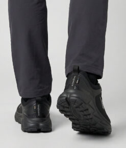 Male model showing off a black bagheera walker walking shoe. The model is standing from behind in a studio with a light gray background.