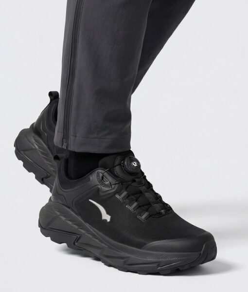 Male model showing off a black bagheera walker walking shoe. The model is standing diagonally from the front in a studio with a light gray background.