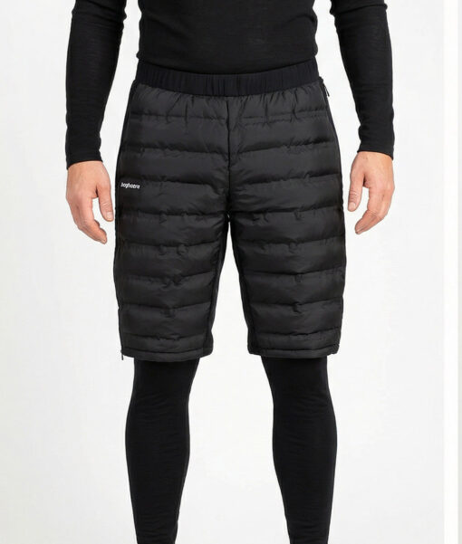 Manlig modell visar ett par svarta vadderade shorts med dragkedja i herrmodell. Modellen har på sig ett svart underställ och står i en studio med ljusgrå bakgrund framifrån.