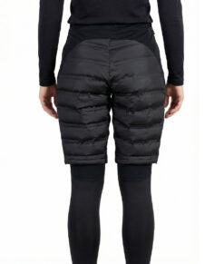 Kvinlig modell visar ett par svarta vadderade shorts med dragkedja i dammodell. Modellen har på sig ett svart underställ och står i en studio med ljusgrå bakgrund bakifrån.