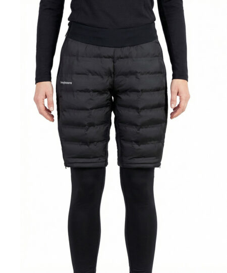 Kvinlig modell visar ett par svarta vadderade shorts med dragkedja i dammodell. Modellen har på sig ett svart underställ och står i en studio med ljusgrå bakgrund framifrån.