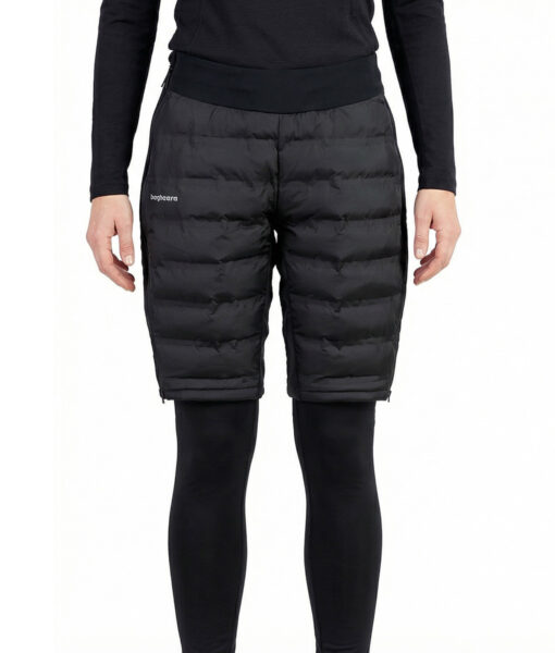 Kvinlig modell visar ett par svarta vadderade shorts med dragkedja i dammodell. Modellen har på sig ett svart underställ och står i en studio med ljusgrå bakgrund framifrån.