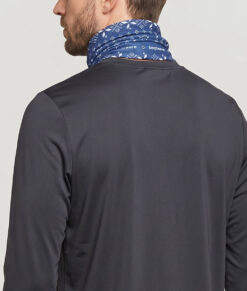 Manlig modell visar en blå Dalecarlianmönstrad tube i en studio med ljusgrå bakgrund. Modellen står bakifrån.