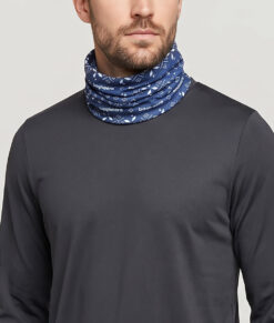 Manlig modell visar en blå Dalecarlianmönstrad tube i en studio med ljusgrå bakgrund. Modellen står framifrån.