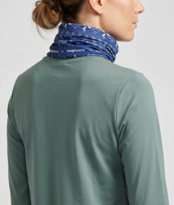 Kvinlig modell visar en blå Dalecarlianmönstrad tube i en studio med ljusgrå bakgrund. Modellen står bakifrån.