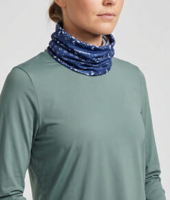 Kvinlig modell visar en blå Dalecarlianmönstrad tube i en studio med ljusgrå bakgrund. Modellen står framifrån.