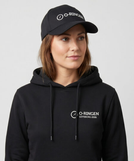 Kvinlig modell visar en svart keps med o-ringen logo. Modellen har på sig en svart o-ringen göteborg 2026 hoodie framifrån i en studio med grå bakgrund.