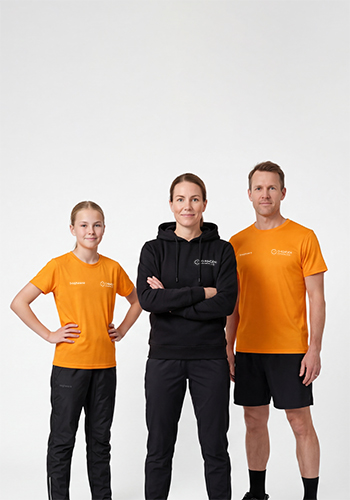 O-ringen 2026 Göteborg svart hoodie och orangea t-shirts. En familj har på sig hoodie och orangea t-shirts och står bredvid varandra i en studio med vit bakgrund.