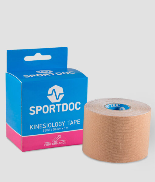 En rulle beige Sportdoc kinesiology sporttape visas framför den tillhörande förpackningen. Tapen visas mot ljusgrå bakgrund.