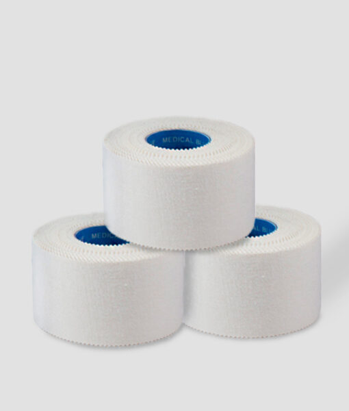 Tre rullar vit Sportdoc medical blue 38mm sporttape. Tapen visas snett från sidan mot ljusgrå bakgrund.