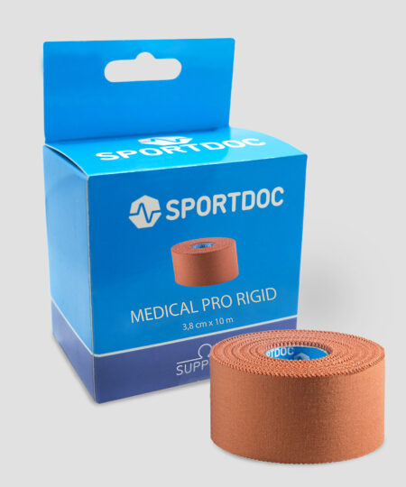 En rulle beige Sportdoc medical pro rigid sporttape visas framför den tillhörande förpackningen. Tapen visas mot ljusgrå bakgrund.