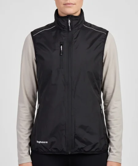 Kvinlig modell visar en svart fleece väst Modellen visar västen framifrån i en studio med ljusgrå bakgrund.