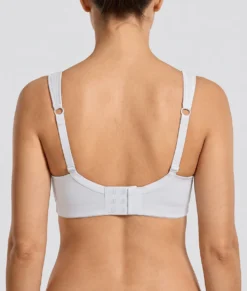 Kvinlig modell visar en vit bh med formpressade kupor och meshdetaljer. Modellen visar bhn bakifrån i en studio med ljusgrå bakgrund.
