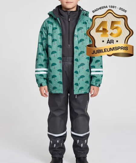 Pojkmodell visar en dimblå fleecefodrad regnjacka och svarta regnbyxor i ett paketpris. Modellen står framifrån i en studio med ljusgrå bakgrund.