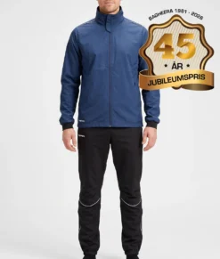 Manlig modell visar Selva marinblå jacka och svarta byxor i ett paketpris. Modellen står framifrån i en studio med ljusgrå bakgrund.
