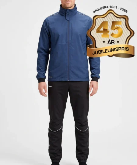 Manlig modell visar Selva marinblå jacka och svarta byxor i ett paketpris. Modellen står framifrån i en studio med ljusgrå bakgrund.
