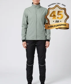Kvinlig modell visar Selva ljusgrön jacka och svarta byxor i ett paketpris. Modellen står framifrån i en studio med ljusgrå bakgrund.