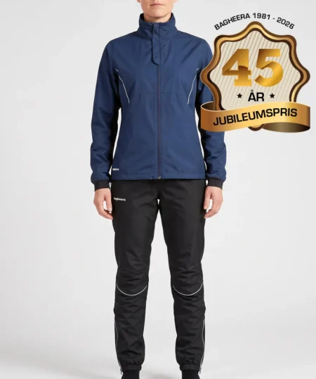 Kvinlig modell visar Selva marinblå jacka och svarta byxor i ett paketpris. Modellen står framifrån i en studio med ljusgrå bakgrund.