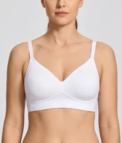 Kvinlig modell visar en vit bh med formpressade kupor. Modellen visar bhn framifrån i en studio med ljusgrå bakgrund.